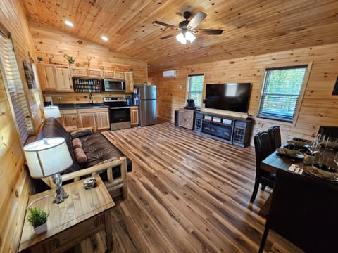 Open living area with futon, dining table, large TV, and full kitchen with stainless steel appliances.