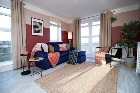 Bright and stylish living space featuring a plush sofa, elegant décor, and large windows, 