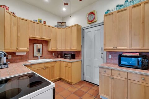 The kitchen offers ample cabinet space, warm tile counters, and modern appliances, creating a functional and welcoming spot to prepare meals or enjoy a quick bite during your New Orleans stay.