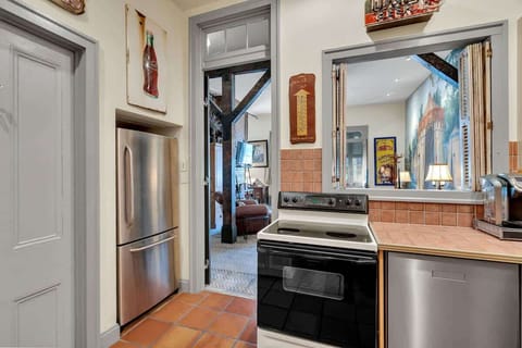 The fully equipped kitchen features modern appliances, warm tile countertops, and charming vintage décor. A pass-through window opens to the living area, keeping the space open and connected while you cook or gather with friends.