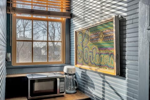 A colorful Mardi Gras bead mosaic spelling out “New Orleans” adds a playful, local flair to the nook, bringing in vibrant purple, green, and gold tones that celebrate the city’s festive spirit.