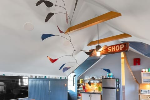 Playful design details shine with a colorful hanging mobile, exposed beams, and vintage sign, adding personality and artistic flair to the loft’s eclectic style.