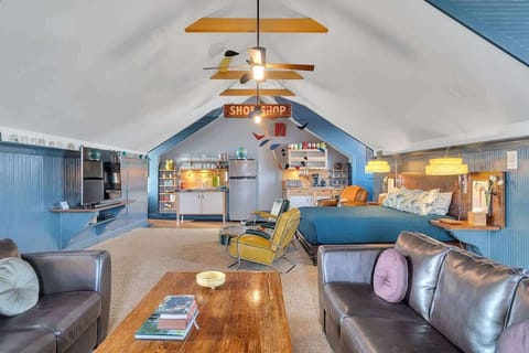 The sleeping area offers a cozy retreat with a queen bed framed by a rustic wood headboard, complemented by built-in side tables and warm, woven sconces. The vibrant teal accent wall adds character, blending comfort with a touch of eclectic charm.