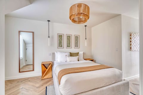 Open sleeping area with a bed, bedside tables and wall art.