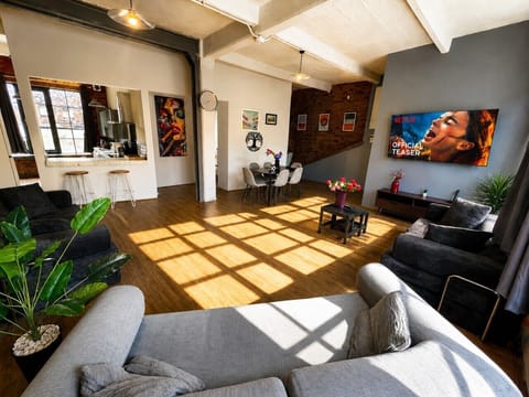 Spacious open-plan living area with comfortable sofas, Smart TV with Netflix, dining space, and large windows filling the apartment with natural light.