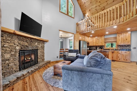 Cozy living area with a stone fireplace, leading to an open-plan kitchen.