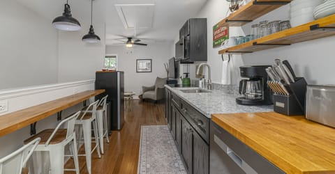 Bright and well-lit kitchen and bar style dining counter with seating for four, featuring a cooktop, apartment sized refrigerator, microwave, and cooking utensils for all your meal preparation needs.