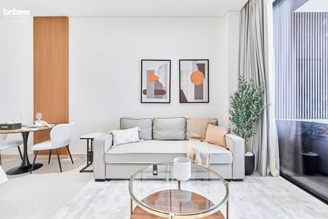 Unwind in the bright and stylish living area featuring a plush sofa bed, modern artwork, soft textiles, and floor-to-ceiling windows that open to a private balcony. Perfect for lounging, reading, or enjoying canal and city views.