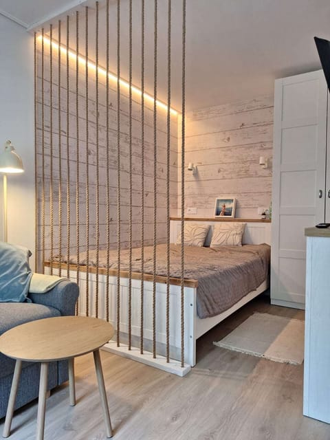 The designated sleeping area, featuring a comfortable bed, is separated by elegant wooden slats that provide a sense of privacy while maintaining the spacious feel of the interior