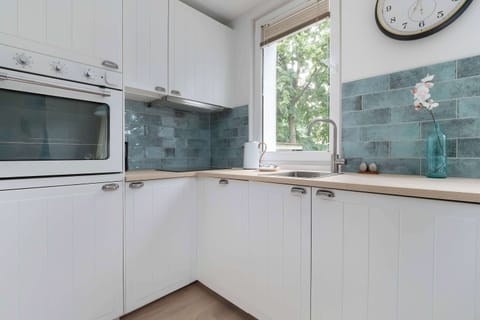 A modern kitchenette with white furniture and high-quality appliances provides space for preparing home-cooked meals.