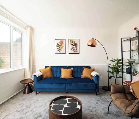 Living Room: Stylish space with vibrant blue sofa, artistic decor, and sunlit views await you!