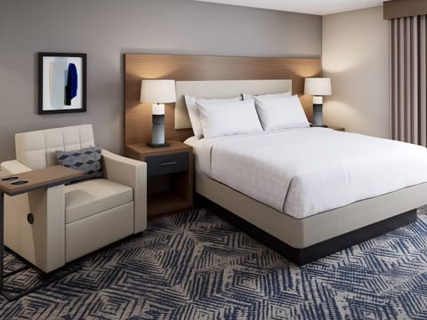 Unwind beneath warm bedside lamps in a serene queen bed.