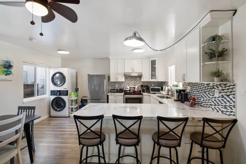 Modern kitchen with island, bar stools, and stacked washer/dryer.
