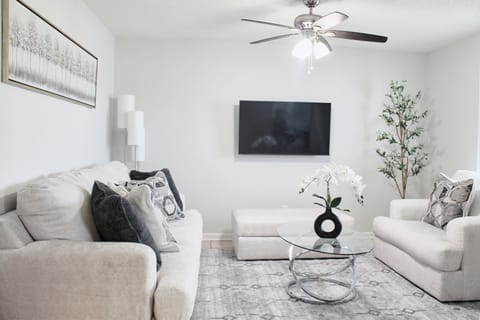 Cozy living room with an oversized chair, ottoman, 3-seater sofa, and smart TV.
