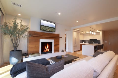 Sink into plush sofas by your crackling fireplace while the modern kitchen awaits your culinary adventures - this open-concept space perfectly blends warmth and sophistication for your ideal retreat.