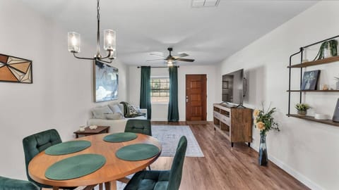 Relax in a cozy living room with plush seating, soft lighting, and warm decor. Connected to a quaint dining area, it features a large TV, perfect for movie nights, unwinding, and conversations with loved ones.