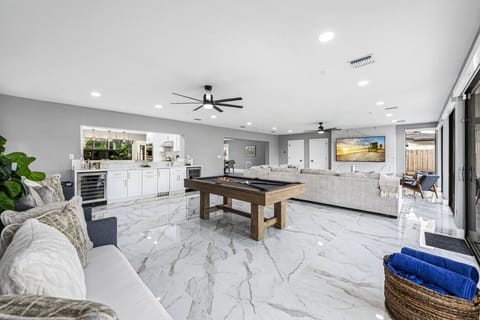 Wide open living space with pool table elegant sofa airy marble floors and glass outlook