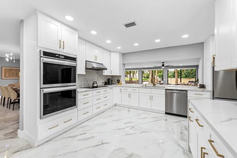 Gourmet kitchen crisp white cabinetry premium appliances and breakfast nook with garden view