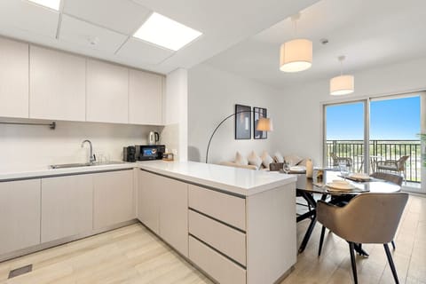 L-shaped kitchen with sleek cabinets and view toward dining and balcony.