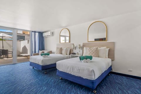 two comfortable full-sized beds with crisp white and blue bedding, accented by turquoise rolled towels at the foot of each bed.