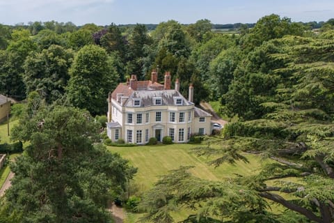 Aerial view of Holbecks House, a Grade II listed Georgian country house near Hadleigh in Suffolk, with lawned gardens and mature cedar trees