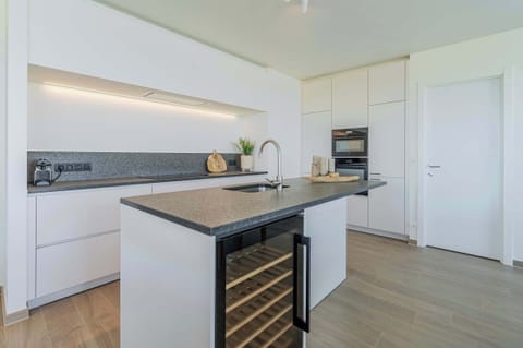 Modern kitchen with wine fridge and clean design.
