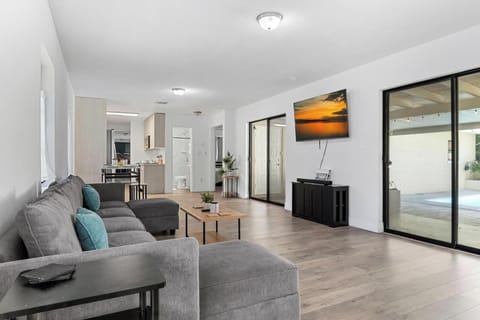 Bright and modern living space with cozy seating, smart TV, and open layout leading to the kitchen and pool area. Perfect for relaxing after a day at the beach or enjoying movie nights with family.