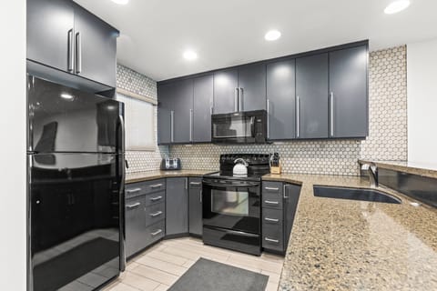 Snow Flower 126 offers a well equipped kitchen with grey cabinets, granite countertops, and tiled backsplash.