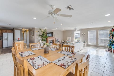 The open dining area seamlessly connects to the bright living room, featuring a warm wooden table and beach-themed decor.