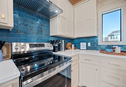 Fully equipped kitchen with stainless steel stove and striking blue backsplash.