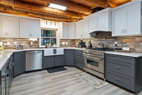 Elegant farmhouse sink, stone backsplash, and premium appliances add modern luxury to this classic log cabin kitchen.