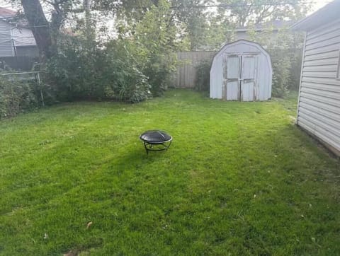 Fenced backyard with fire pit, space for soccer, and picnic area.