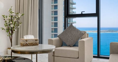Cozy armchair in the living room with a stunning backdrop of the sea view at sunset, framed by the large window for a serene and picturesque view.