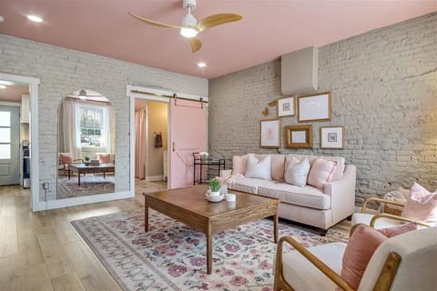 Chic living room with pink velvet couch, pink accents, and an oversized mirror.