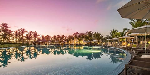Sip cocktails poolside as sunset colors glow across water.