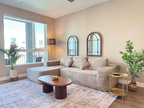 Spacious living room featuring a cozy L-shaped sofa, a full-size air mattress, and a 65" Smart TV with preloaded access to Netflix, Hulu, and Disney+, all set up for your enjoyment.