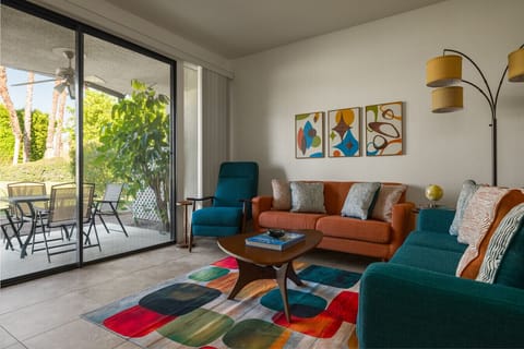 Feel at home in this cheerful living room with colorful sofas and creative wall paintings that add personality.