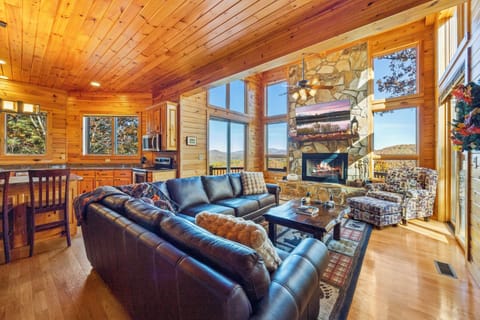 Open-concept living room with stone fireplace and panoramic mountain views.