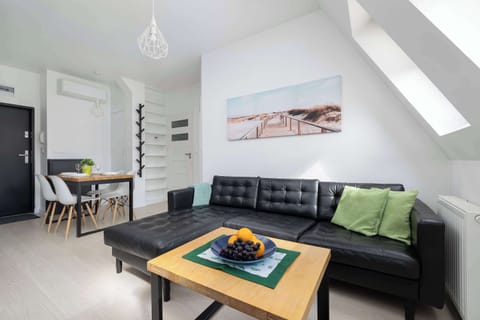 An elegant living room filled with natural light, featuring a modern black sofa, stylish wooden coffee table, and tasteful artwork creating a welcoming atmosphere.