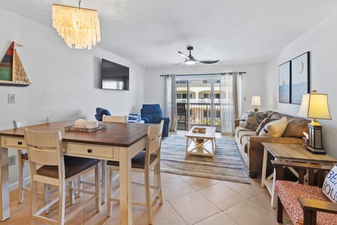 Relax in this bright beach-inspired living and dining area featuring coastal décor, comfy seating, and balcony access—perfect for unwinding after a fun day at the shore.