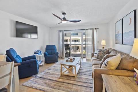 Unwind in this inviting beach-style living room featuring cozy seating, coastal décor, and balcony access—perfect for relaxing after a sun-soaked day by the ocean.