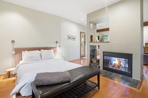 Serene bedroom with double-sided fireplace and hardwood floors