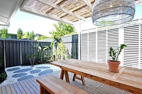 A timber dining bench, soft filtered light, and leafy views—alfresco simplicity at its best.