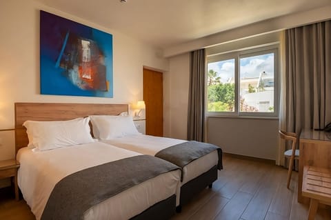 Recharge in twin beds beside bright windows and leafy outlook