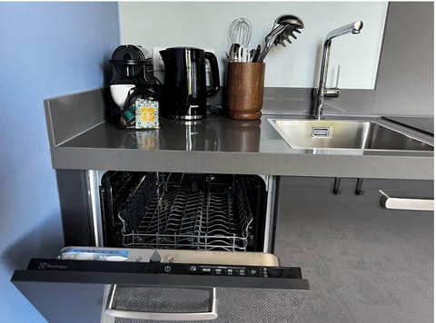 Fully equipped kitchenette with dishwasher, kettle, and coffee maker.