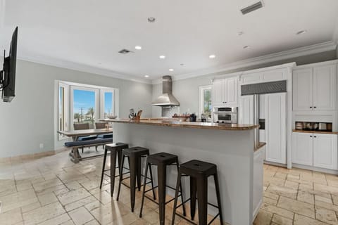 Pristine white cabinets, seats to chat with the chef, and a wooden table and bench combine for a unique, spacious kitchen.