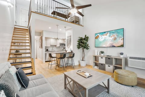 Bright and airy living room with soaring ceilings, stylish loft, and open kitchen — perfect for relaxing or entertaining.
