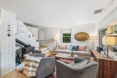Main living room area, including sofa, wood burning stove, swivel barrel chairs.