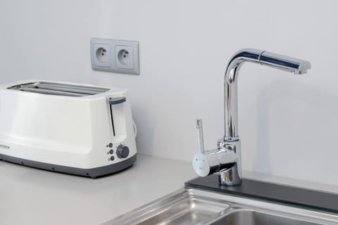 A white toaster placed on a kitchen counter near a power outlet. Simple and practical detail of the apartment.