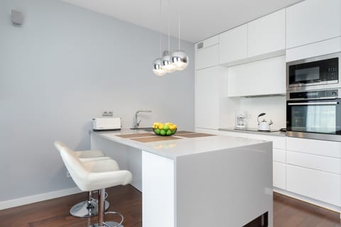 A shiny chrome faucet over a clean sink, reflecting the modern kitchen design. Minimalist style emphasizes neatness.